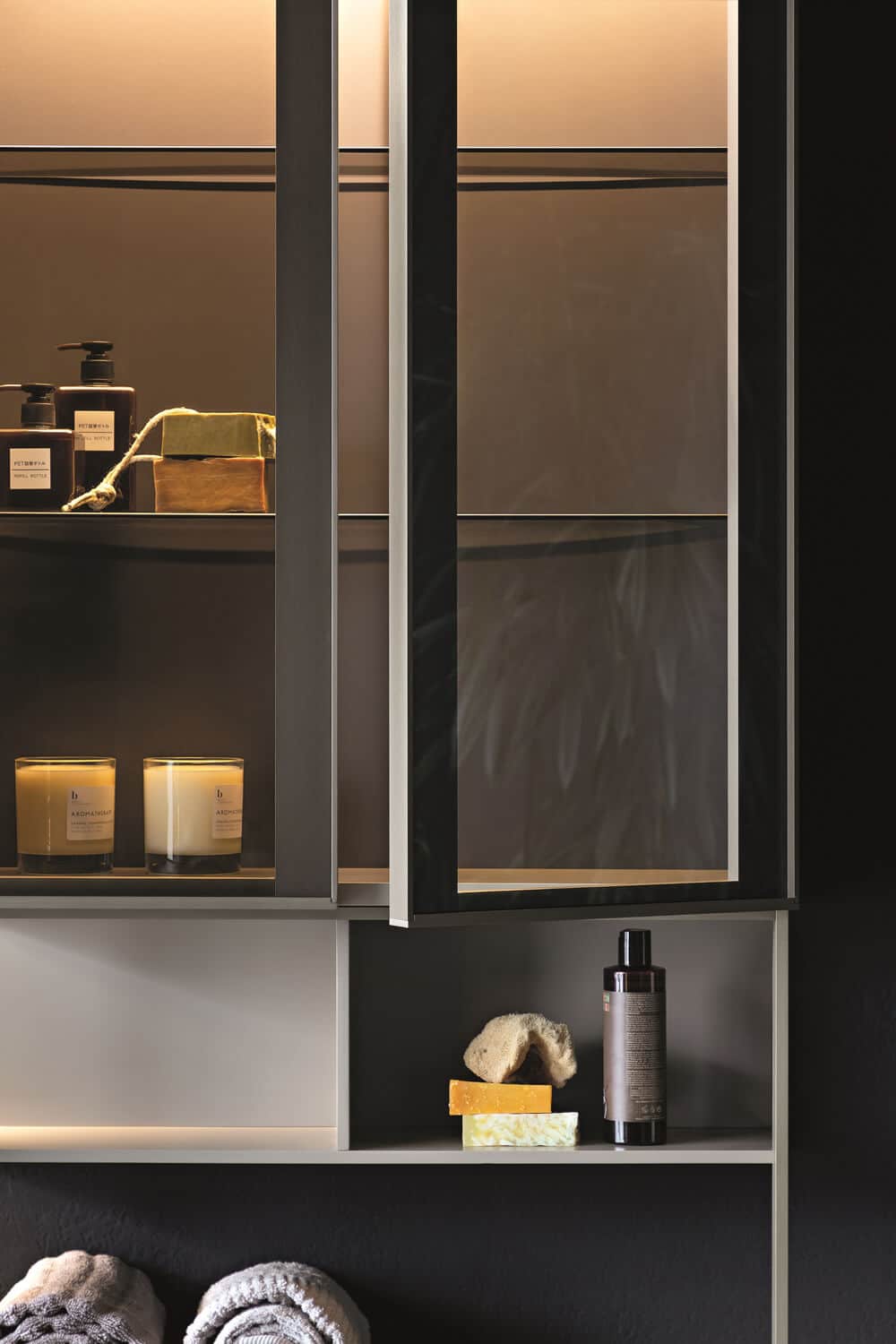 Internal lights and doors in burnished glass contribute an elegant ambiance to the bathroom.