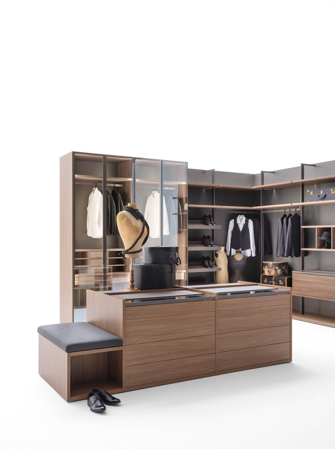 The Cabina luxury walk-in closet system features an open top. Pair it with Core modules with solid and framed glass doors. The double-sided island unit is customizable with glass-top drawers, open elements, leather inserts, and integrated stools. Shown: Easy Walnut veneer and piqué melamine finishes. 