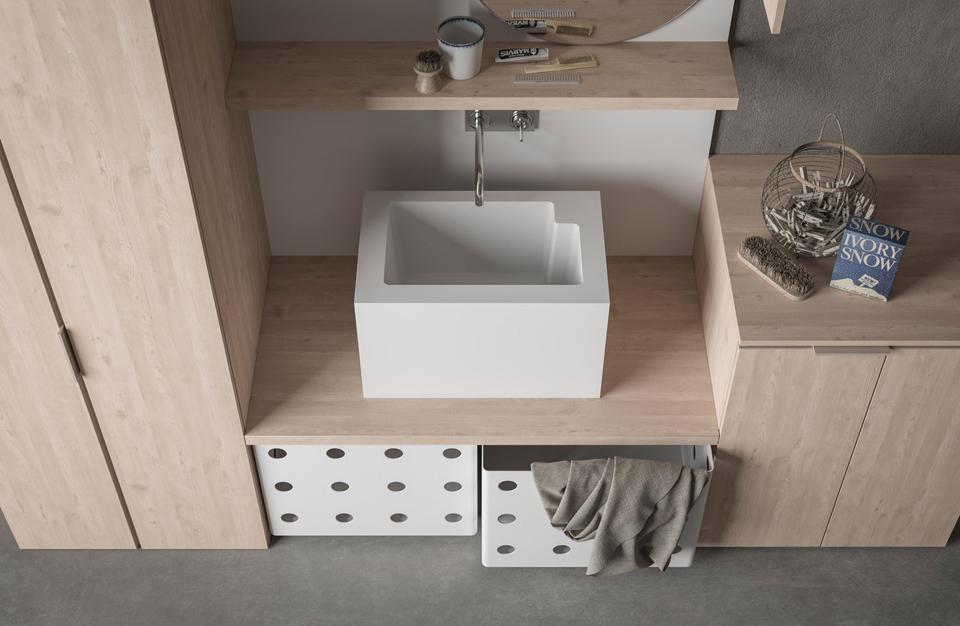 A modern laundry room with a white sink, wooden cabinets, and laundry baskets.