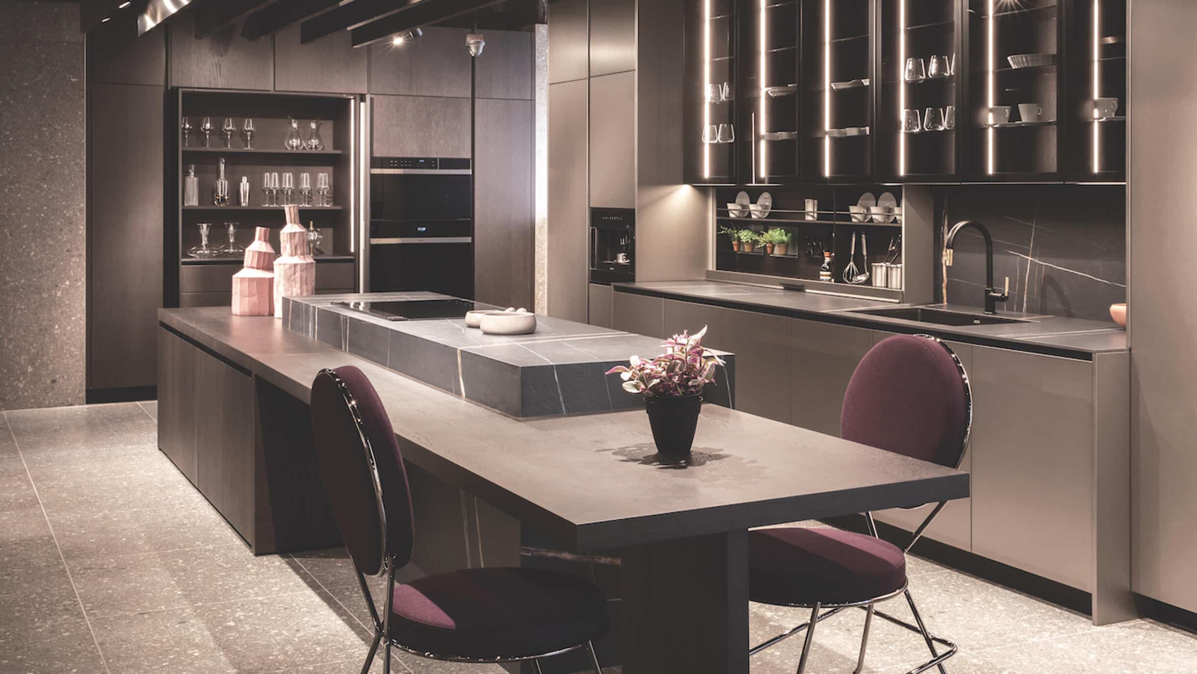 Modern kitchen with dark cabinets, a large island, and a marble countertop.