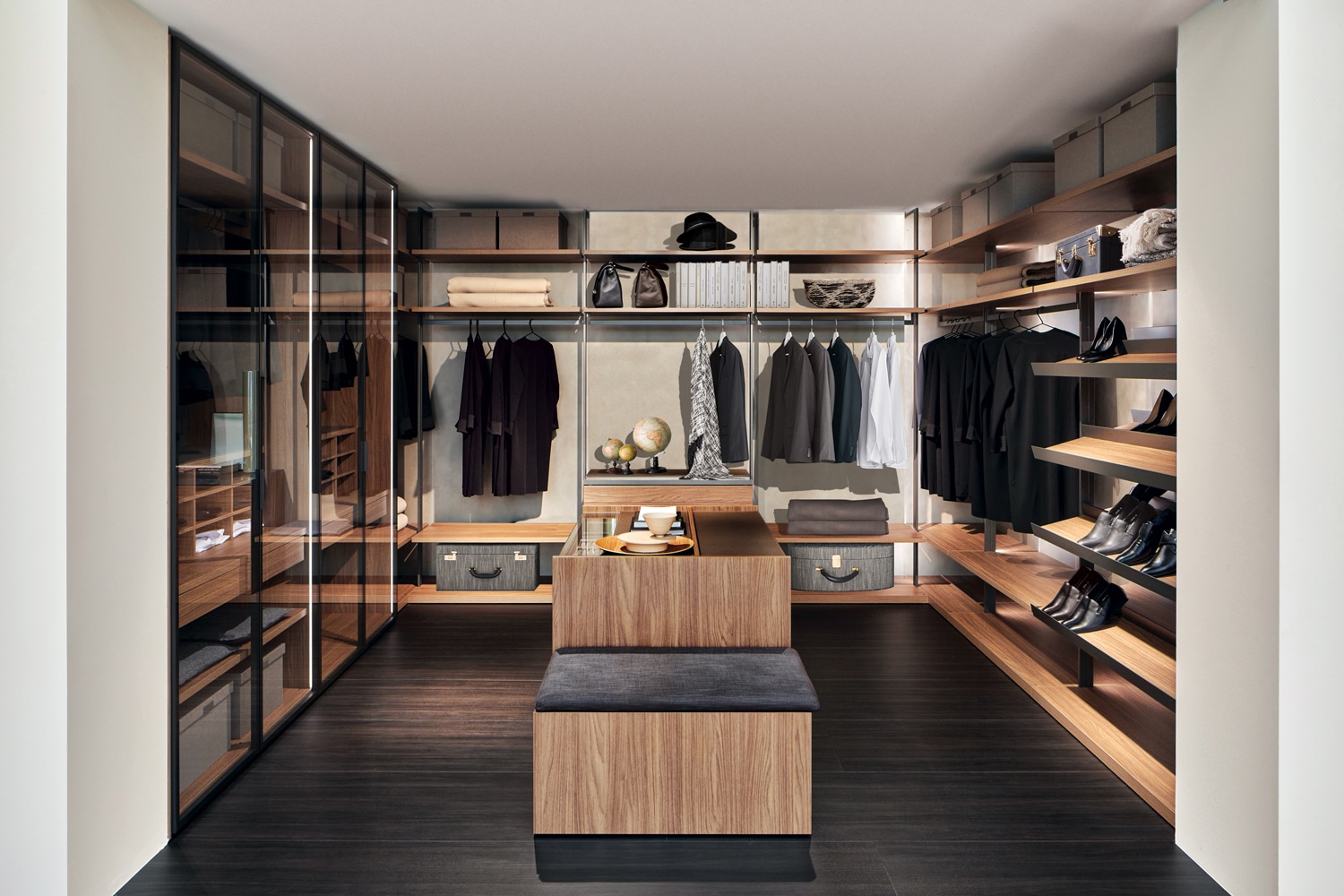 Walk-in closet in Easy Walnut, Ferro Oxid, and Ombra matte lacquer. Island at the center. Closed modules on the left with doors in framed fume' glass.