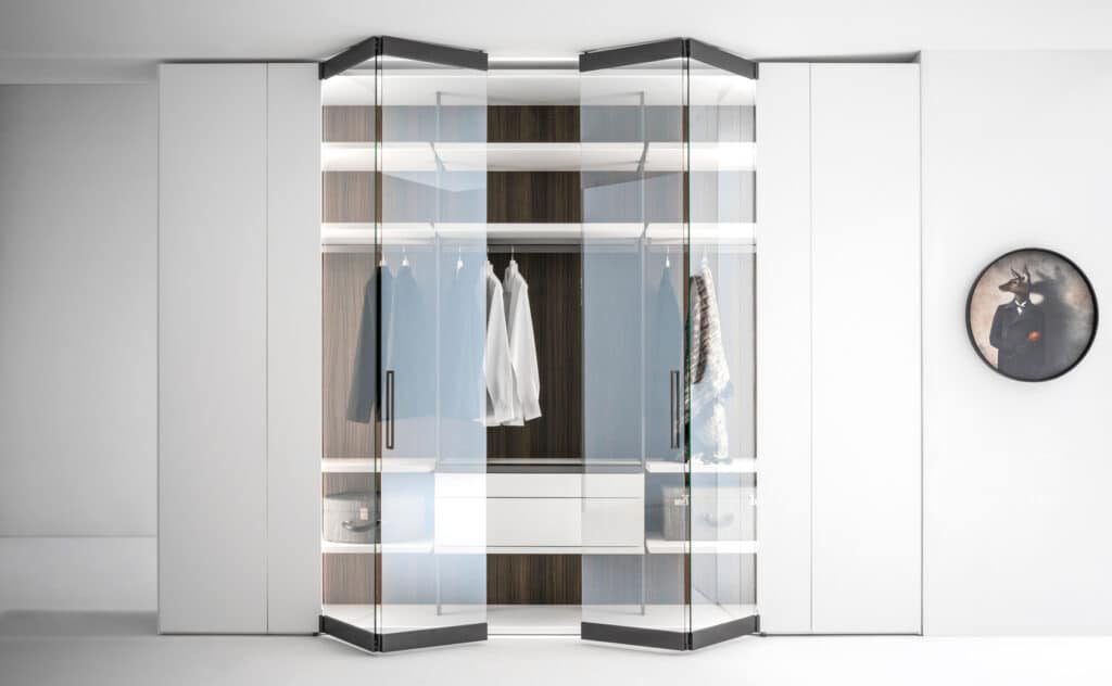 A modern walk-in closet with glass doors and wooden shelves.