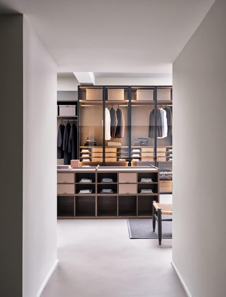 Luxury walk-in closet with glass door modules and central island with drawers, open shelves and removable fabric drawers.