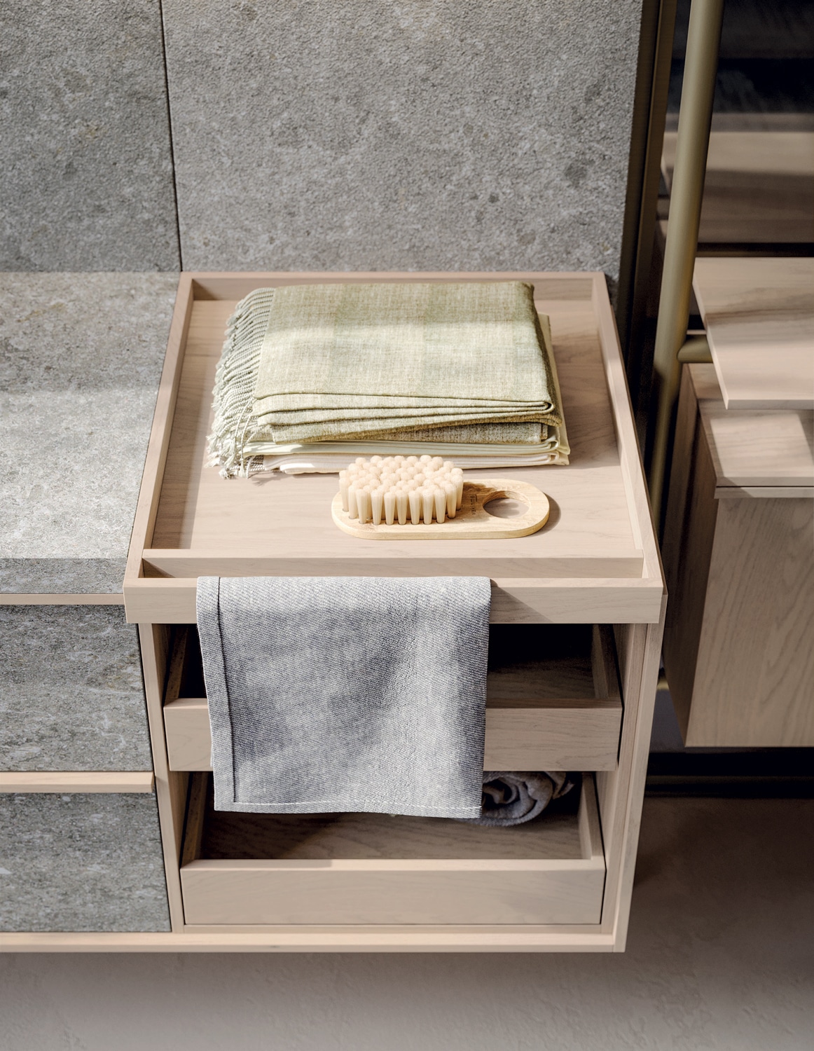 The floating vanity in Meteora Gris ceramic extends to one side with an open storage unit in Avena oak to match the cabinet frame.