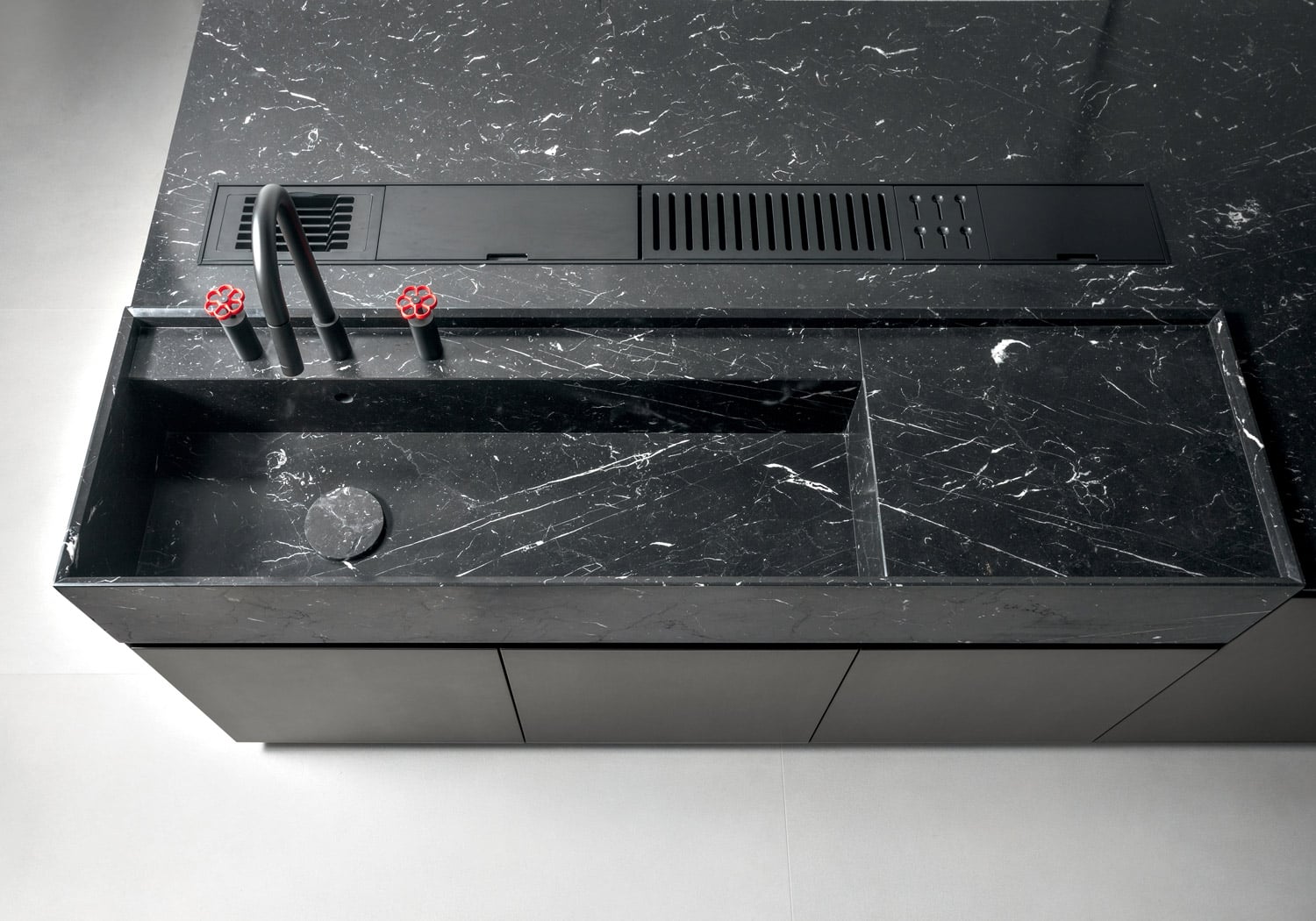 Even if made in the same material, sink and countertop are designed to be two distinct areas of the kitchen island. In front of the sink, also integrated within the countertop, is a custom accessorized channel to store knives, dishes and more items. 