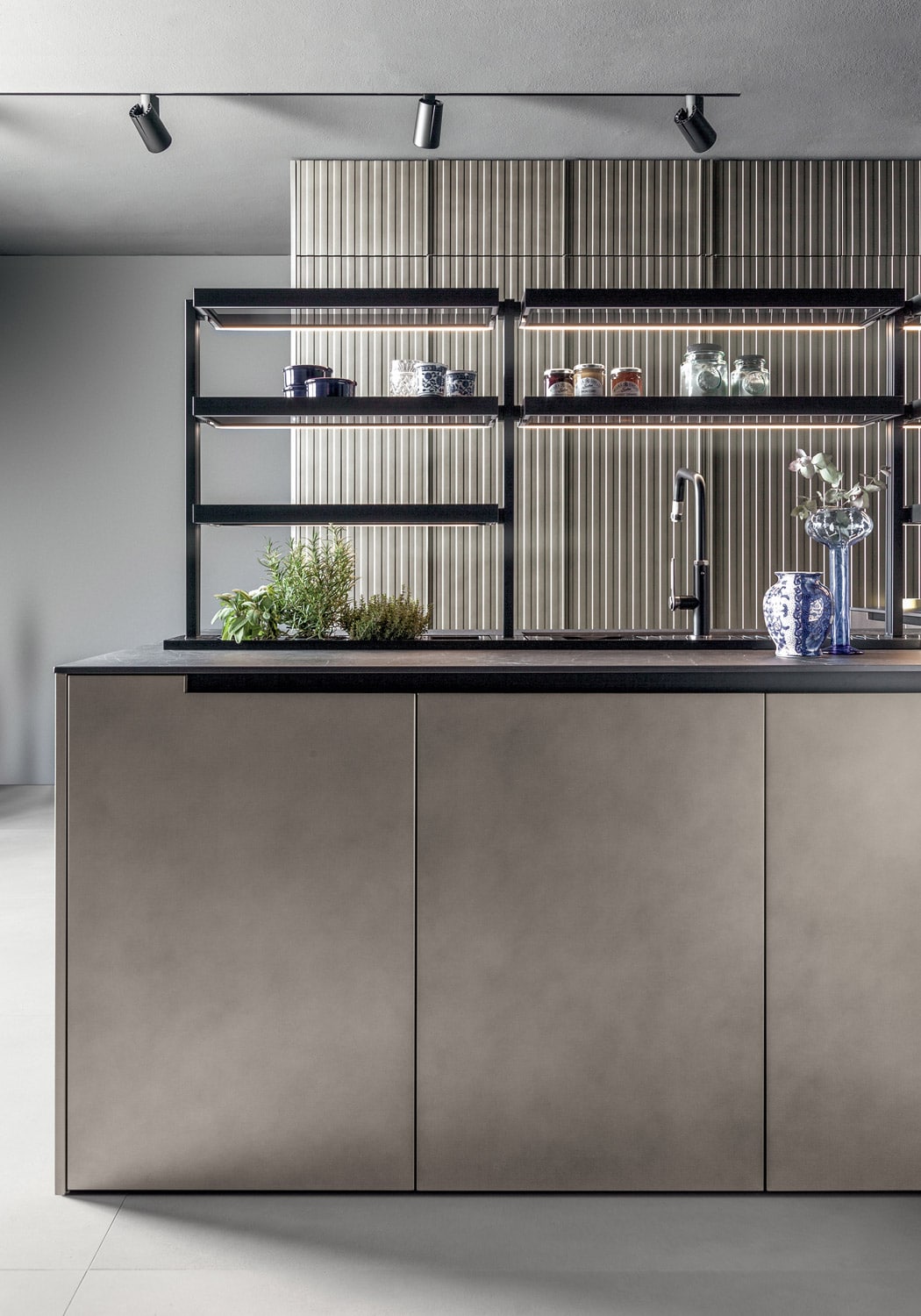 On the island, the customized open storage system features lit glass shelves with profiles in black anodized aluminum.