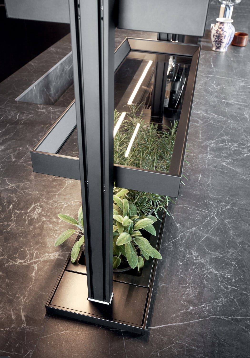 Detail of the custom open storage system. The black anodized aluminum profile angles inward towards the glass shelves to prevent objects from falling.