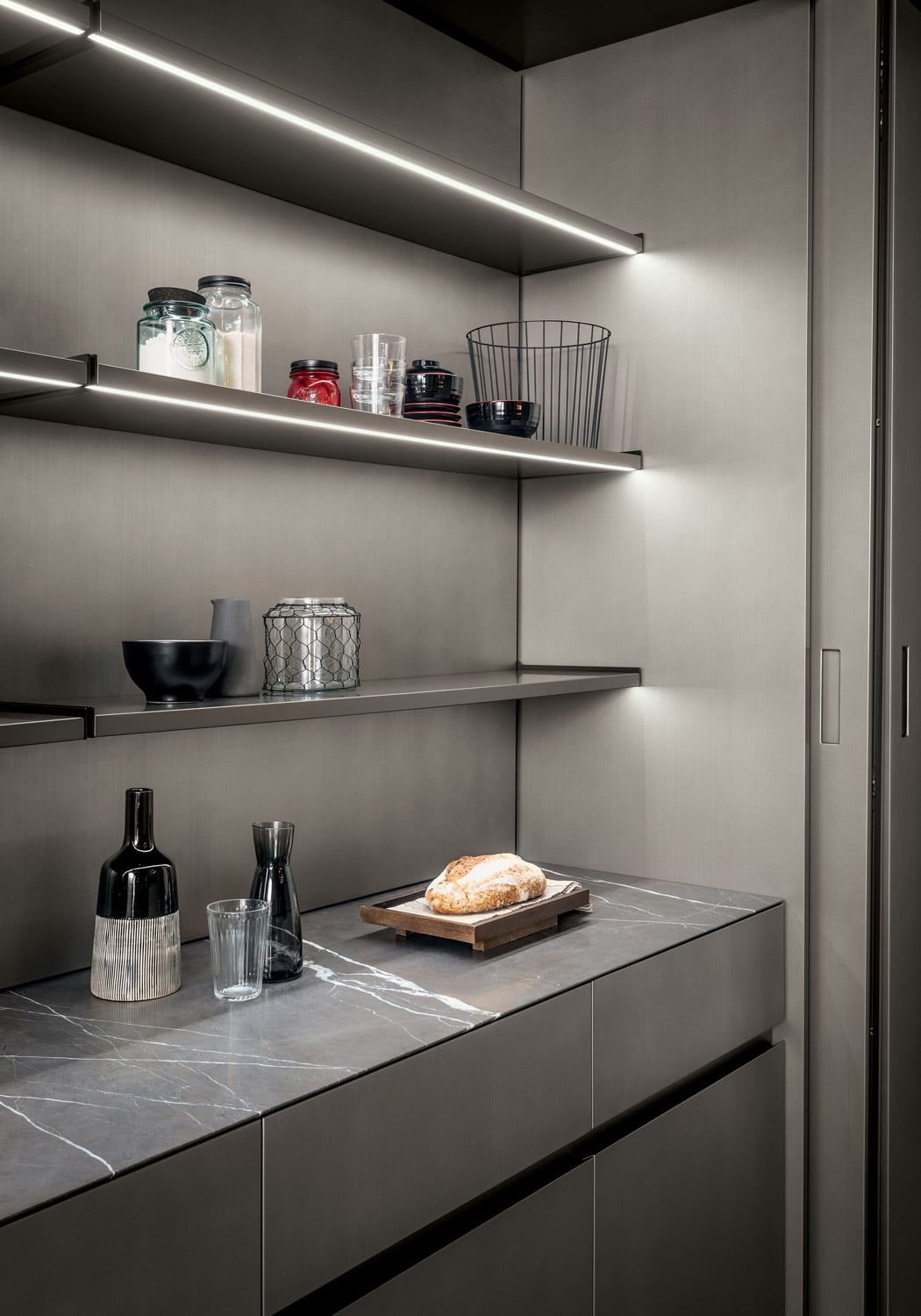 Inside the central section of the tall units, the extra surface features a Pietra Grey marble finish. Under the shelves are LED strips custom fitted towards the front of the shelves. 