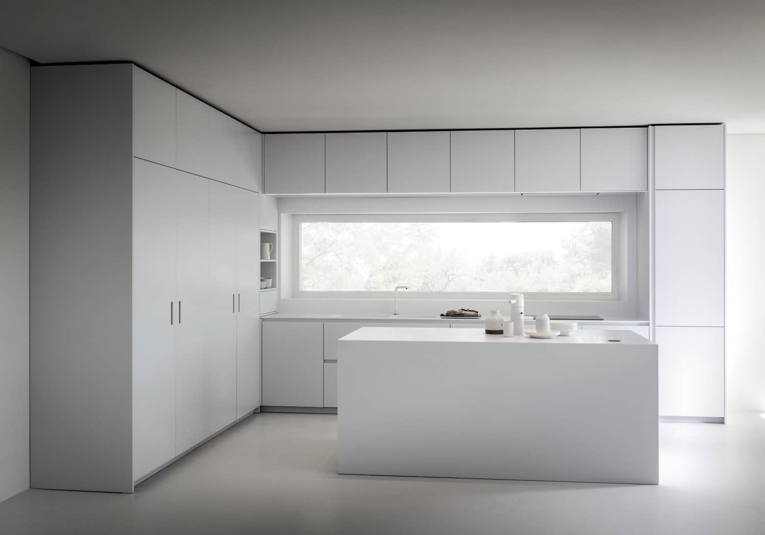 Cabinet doors are in RAL9003 White matte lacquer. Designer White Corian was used for countertops, island, and the frame around the window. 