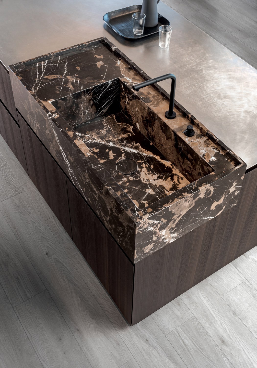The marble sink block is set against the island countertop in vintage finished stainless steel. 