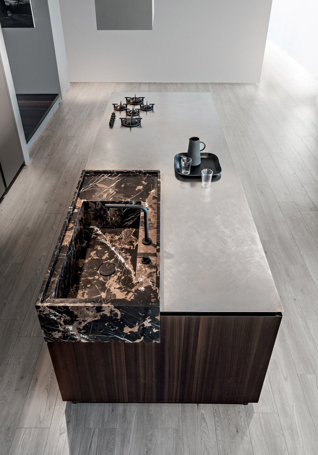 The marble sink block is set against the island countertop in vintage finished stainless steel. 
