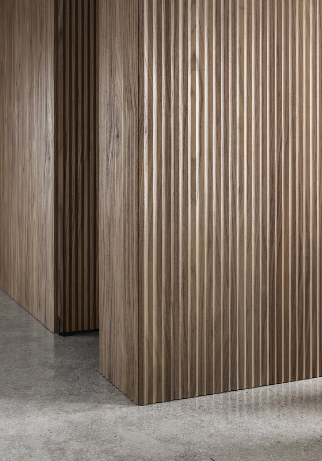 All kitchen storage remains hidden behind the beauty of the ribbed Canaletto Walnut panels.