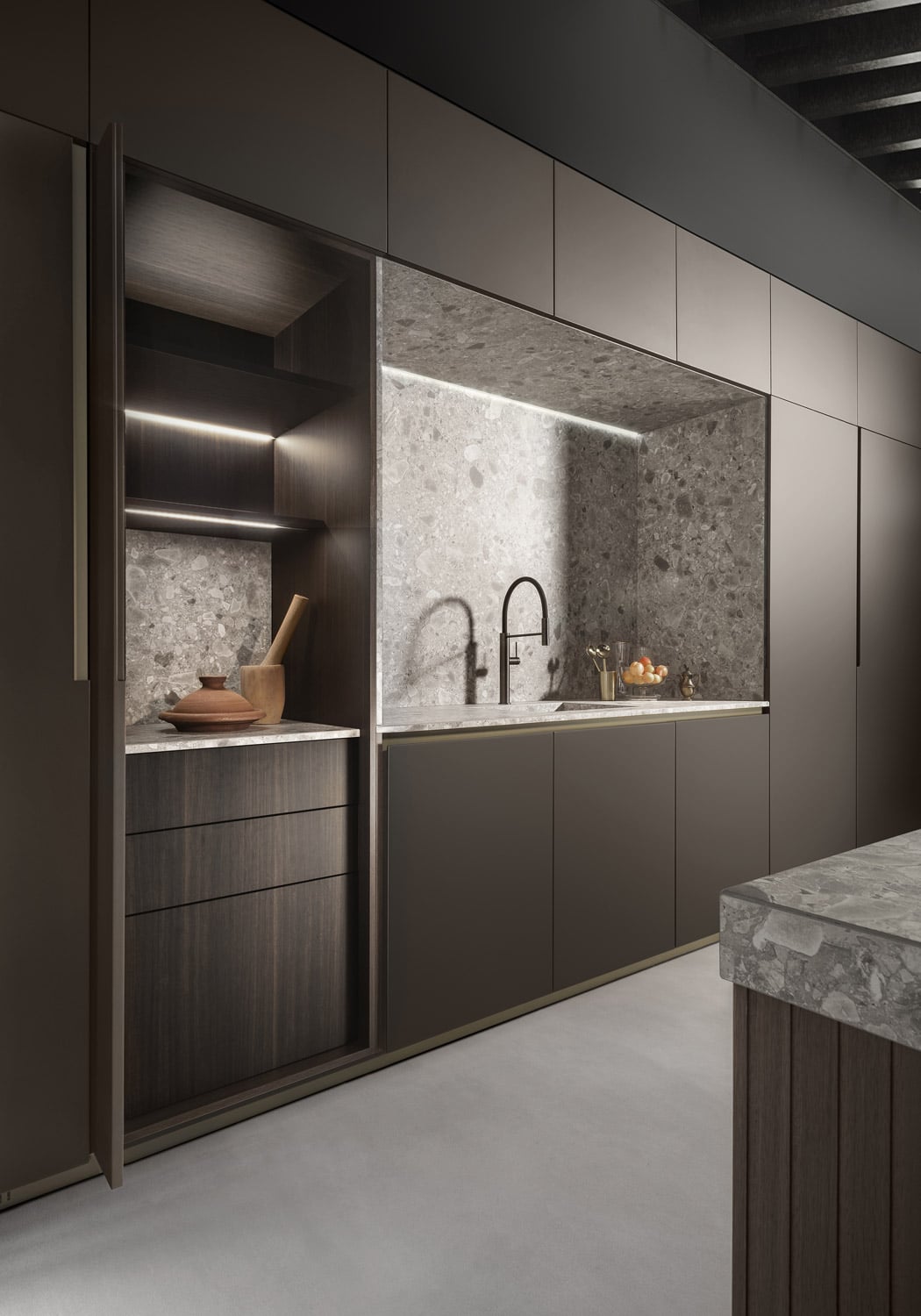 With its Atlas Kone Mix stoneware finish, the washing area becomes a focal and architectonical point of the kitchen. On both sides of it are custom storage units with single pocket doors. 