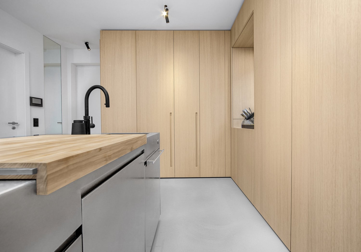 Tall unit with Oslo recessed vertical handles combining a pocket door and bifolding pocket doors to accommodate the non-standard dimensions of the space. 