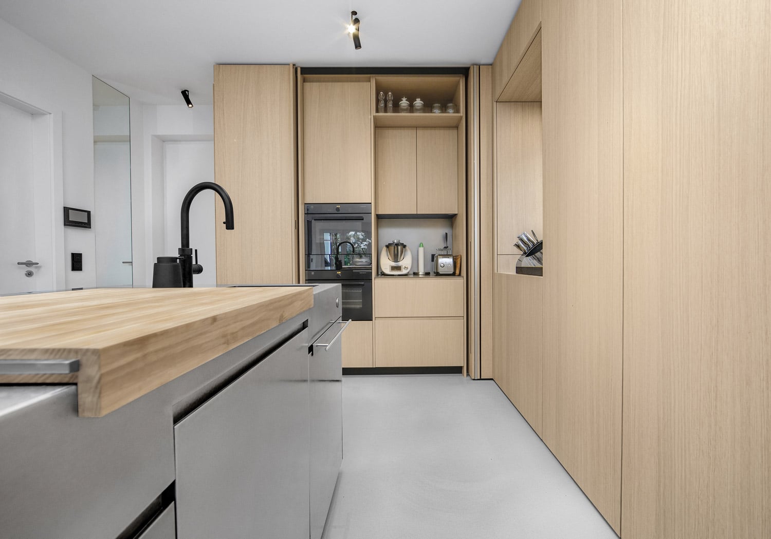 The right side of the unit features a bifolding pocket door to go with its slightly larger width. Each side is customized in functionality. Using the same finish in the interiors as in the exterior maintains the harmonious aesthetics of the kitchen even when the units are in use. 