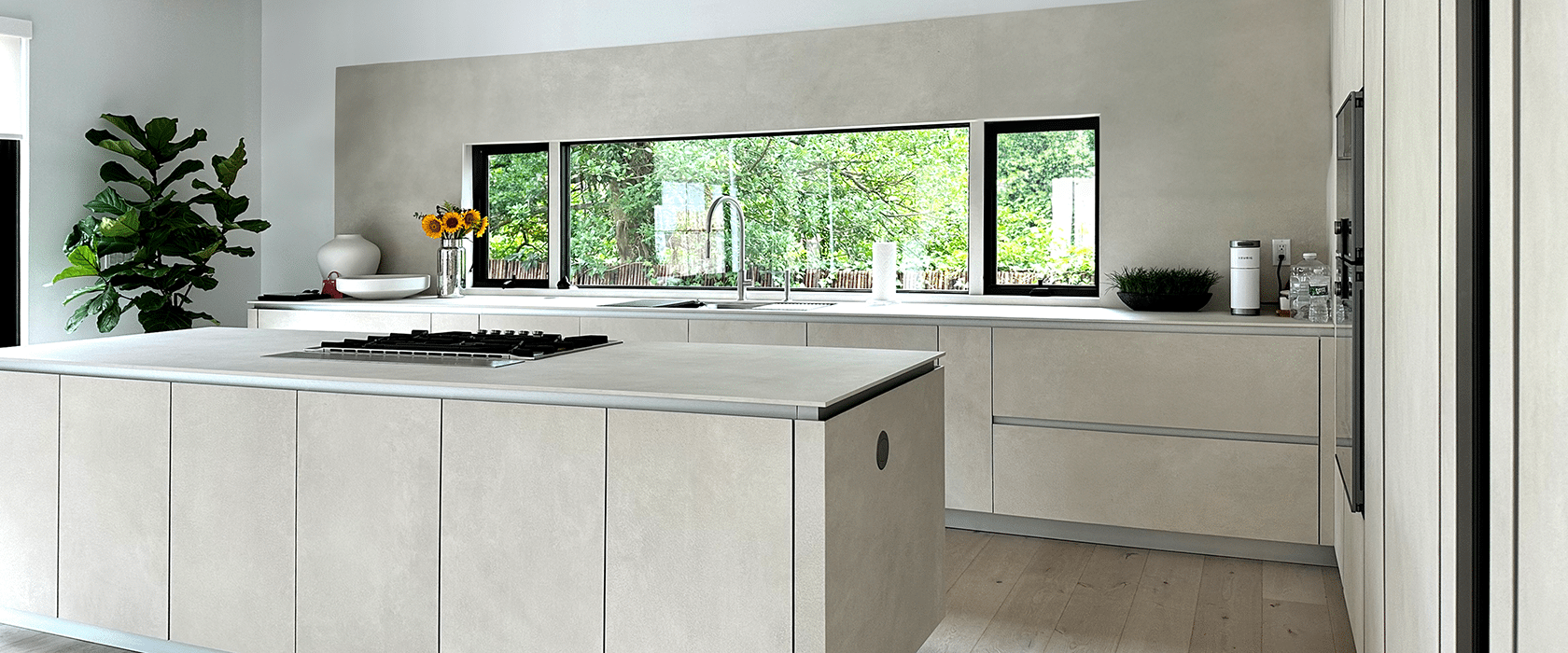 Modern kitchen with light wood cabinets, a large island, and a view of the garden.