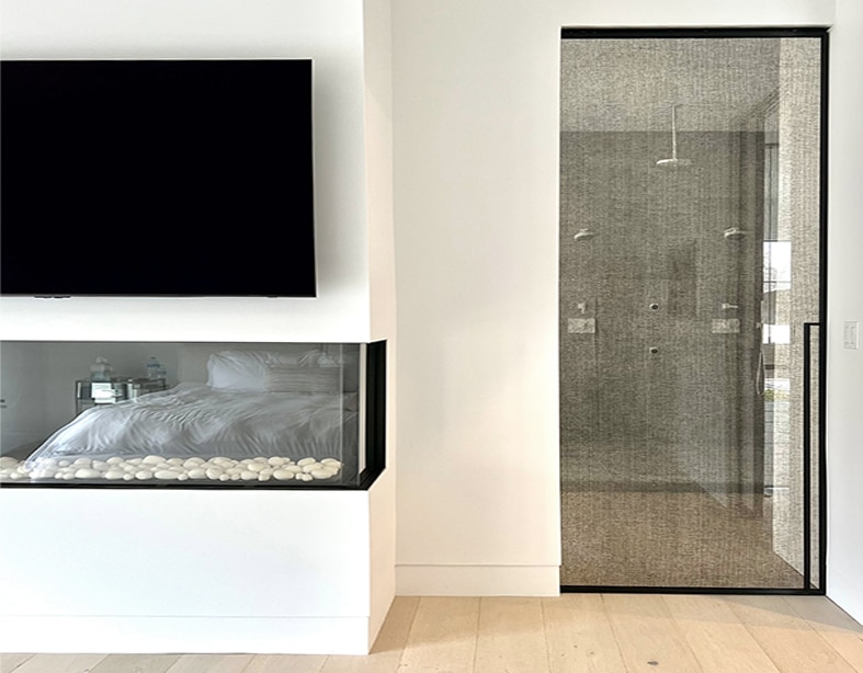 Modern bedroom with a glass-walled shower and a fireplace.