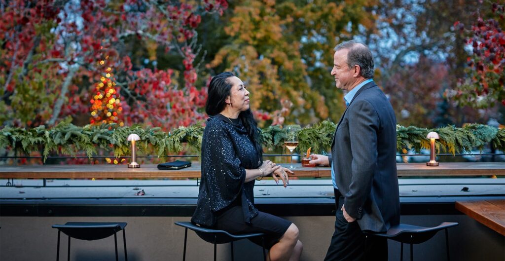 Elegant couple having drinks on a terrace surrounded by trees