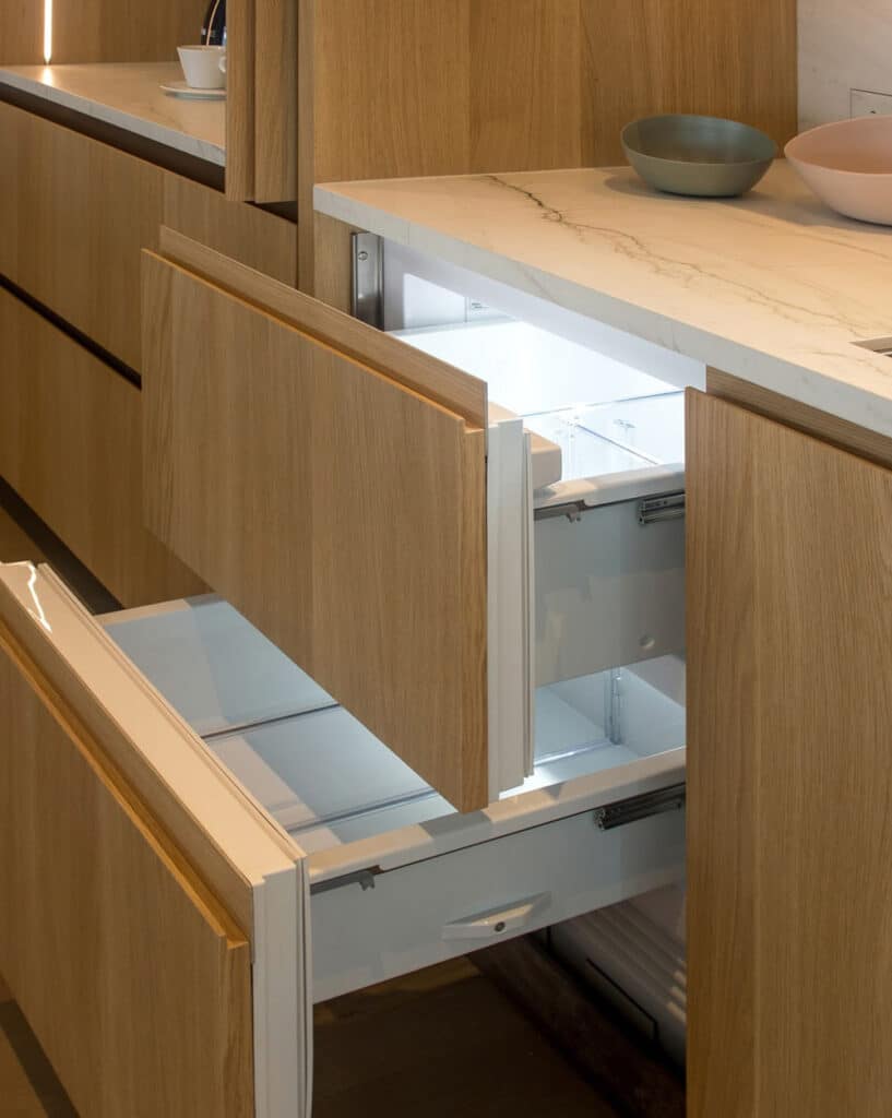 Refrigerator units fitted inside custom cabinets in light oak wood